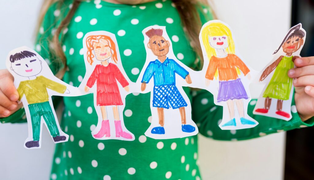 girl holding paper homemade garland of people of different races. Happy international children day