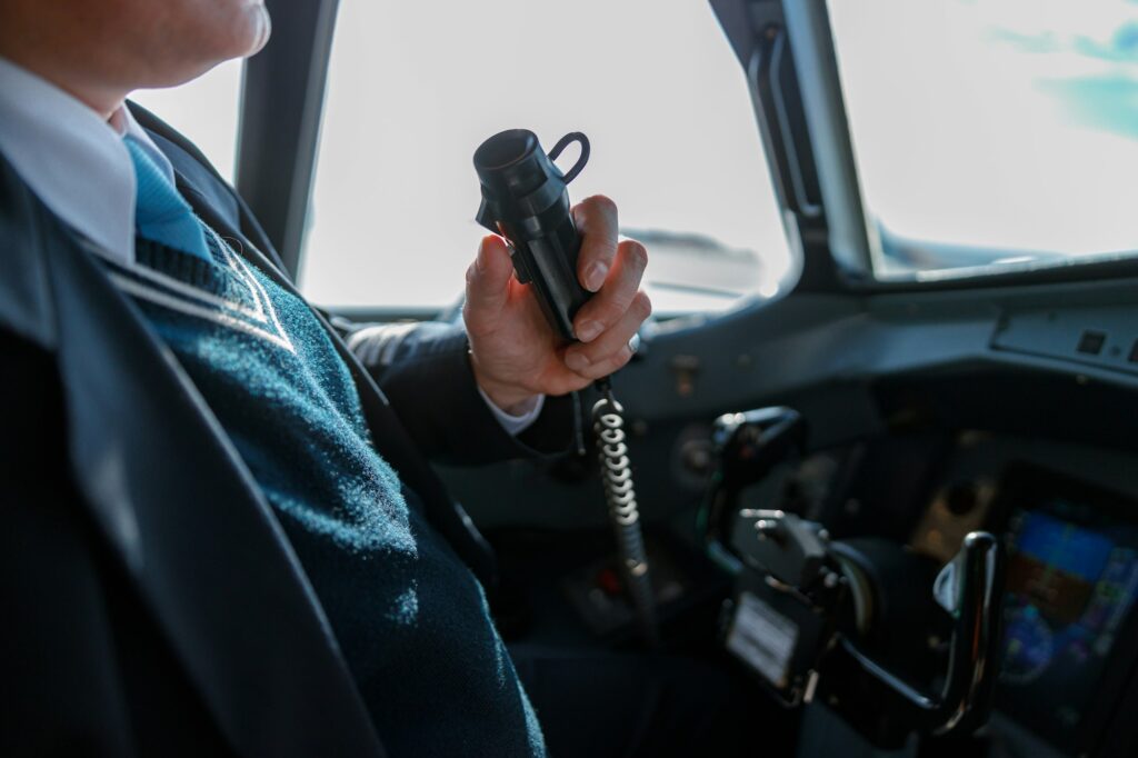 Male pilot using aircraft radio microphone in cockpit