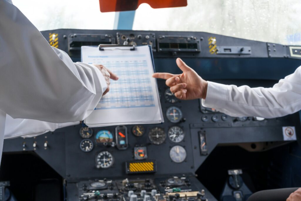 Mature male and female pilots meet inside an airplane, holding hands. Their gesture signifies