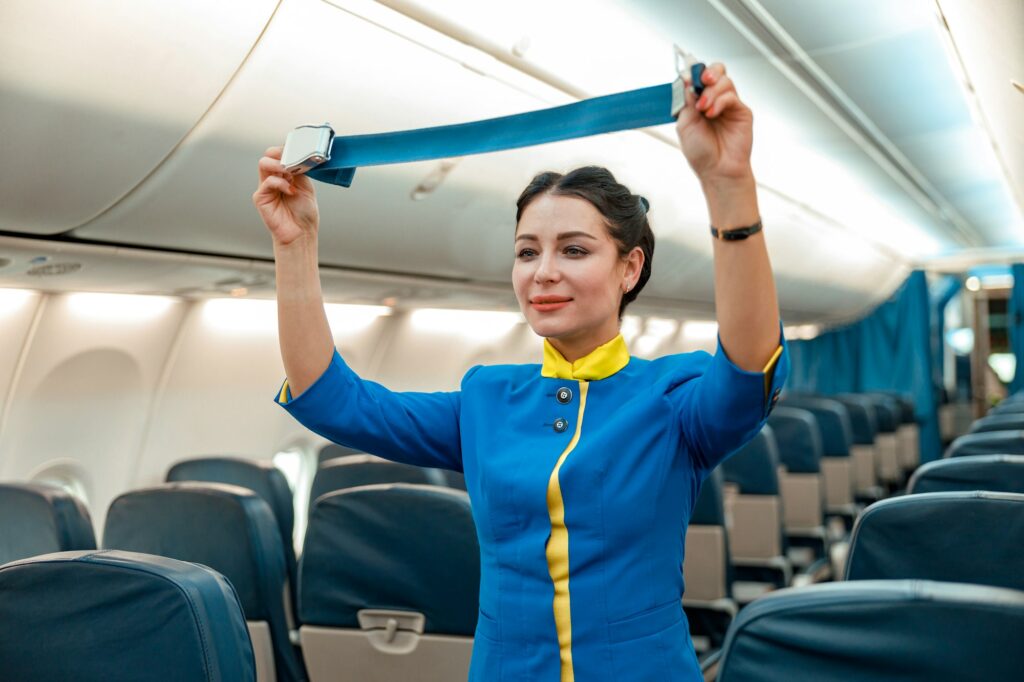 Woman stewardess demonstrating seatbelt in aircraft cabin